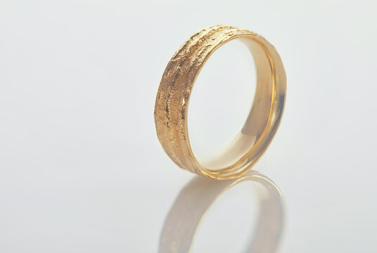Jewelry making. Yellow gold wedding ring with an unusual texture standing on a white background.