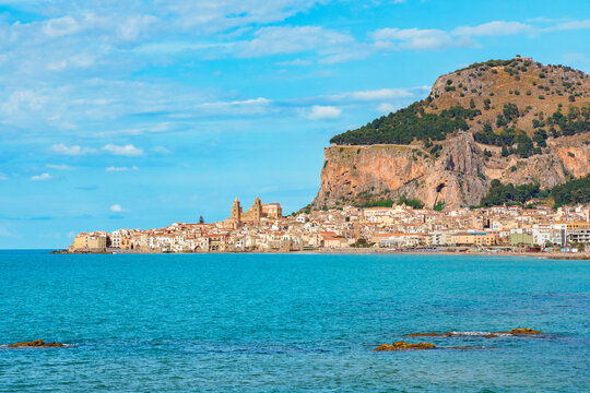 Picturesque coastal town nestled beneath a dramatic rocky cliff by the sea