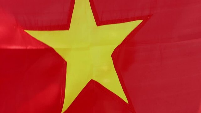 Red flag with a yellow star flutters in the wind, close-up view. Flag of Vietnam.