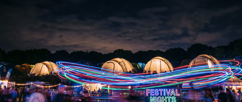 Dynamic Long Exposure Neon Light Trails at Illuminated Night Festival Campsite