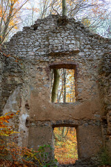 Fototapeta premium Weathered stone and brick gate ruins associated with the historic Carmelite complex near Devil’s Bridge in Czerna, Lesser Poland. Ancient masonry openings frame colorful autumn woodland in Eliaszówka 
