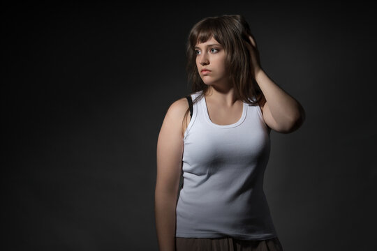 Portrait of a young woman in white tank top looking away thoughtfully