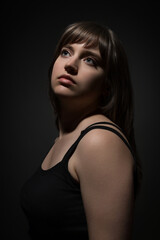 Fototapeta premium Portrait of a beautiful teenage girl posing in beauty style against a dark background