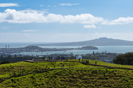 Visitors walking on the summit boardwalk of Mount Eden with the city, harbour and Rangitoto Island in the background, Auckland, New Zealand