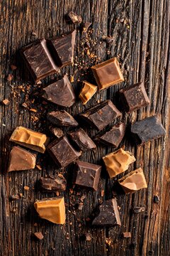 Broken chocolate chunks with rough edges on rustic wooden boards