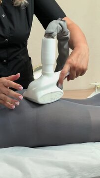 Beautician performs LPG body massage on a woman's buttocks for cellulite treatment, body contouring, slimming therapy, professional cosmetic care.