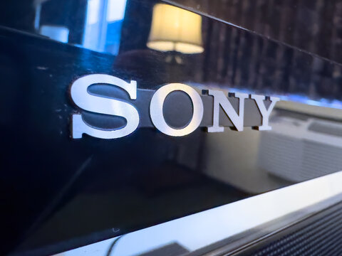 Ottawa, Ontario, Canada. August 21, 2026. Extreme close up of silver Sony logo on glossy black television frame displaying room reflection.