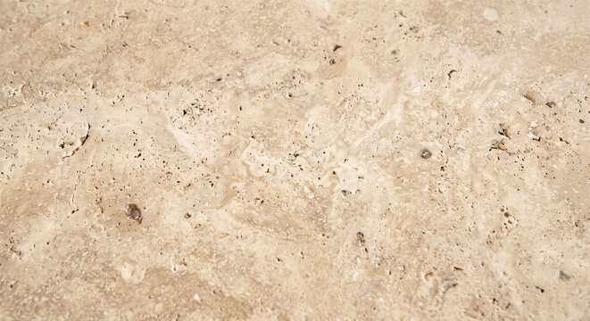 Beige travertine stone texture displays porous surface details in close-up top view for natural backgrounds