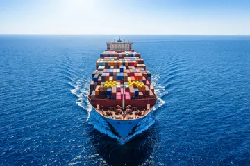 Aerial front view of a heavy loaded, large super cargo container ship sailing over the ocean © moofushi