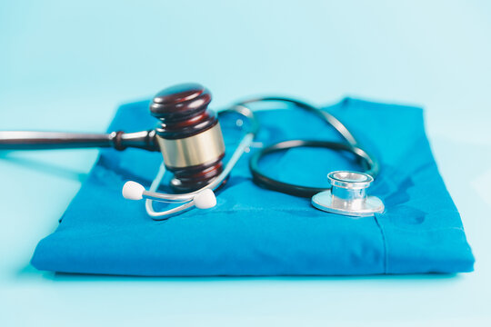 Judge gavel and stethoscope arranged on blue medical scrubs, representing healthcare law, medical malpractice, clinical regulation, professional liability, patient rights, compliance,