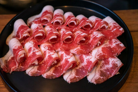 A hotpot meat platter presents thinly sliced beef, pork, and chicken arranged neatly on a serving plate. Close-up compositions emphasize beef marbling, pork color, and the natural fiber patterns of ch