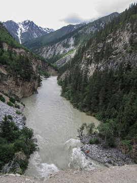 Mountain river flowing through a deep and narrow gorge surrounded by green trees