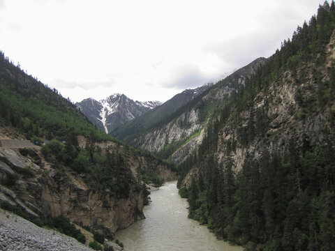 Mountainous valley with river and snow-capped peaks in the distance