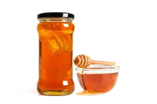 Glass jar of  fresh golden honey with honey comb, and glass bowl and  wooden dipper. Isolated on white for organic food .