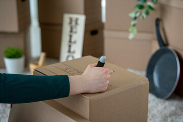 Fototapeta premium Woman Labeling Moving Box as Kitchen During Home Relocation