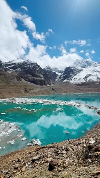 4K Vertical shot of Turquoise colored Ghepan Ghat Lake during the summer season with icebergs fallen from the glacier floating in the water near Sissu in Lahaul Valley, Himachal Pradesh, India.