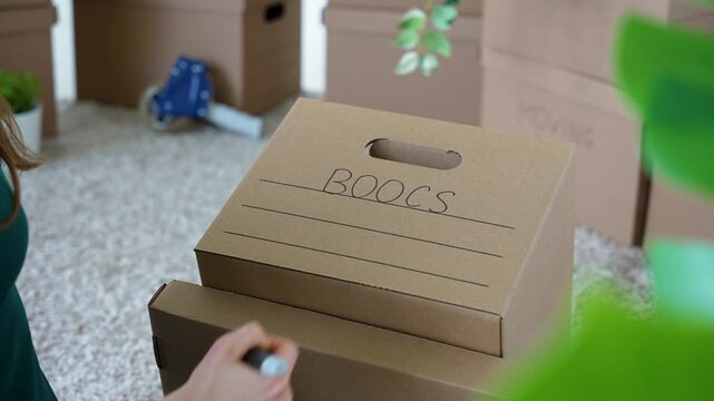 Woman Making Spelling Mistake While Labeling Moving Box