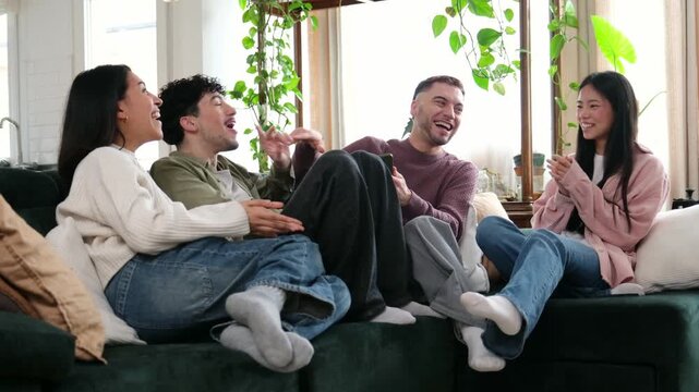Diverse group of young adult friends enjoying a cheerful conversation and laughing together at home