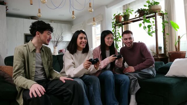 Four happy diverse friends sitting on a sofa and having fun playing a competitive video game