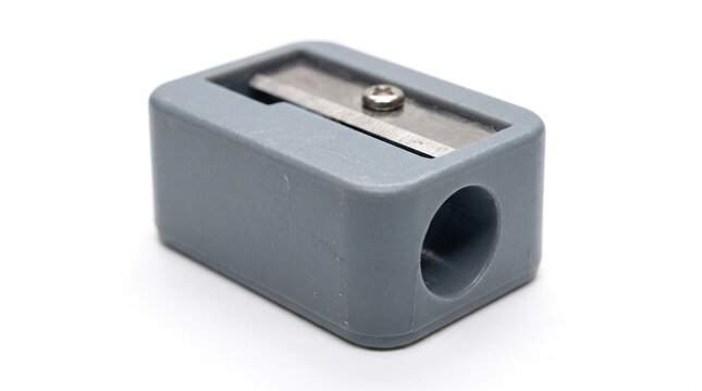 A classic grey plastic manual pencil sharpener featuring a sharp metal blade and a simple functional design, ideal for school stationery and office supply concepts.