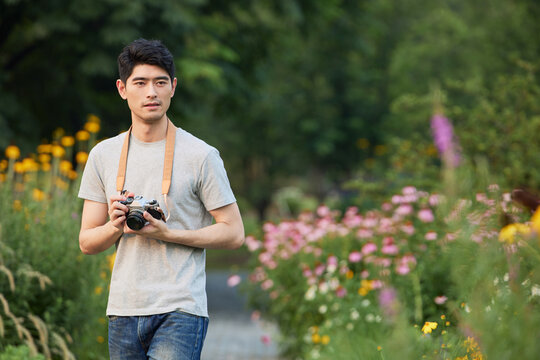 Young man with camera in a flower garden path outdoors