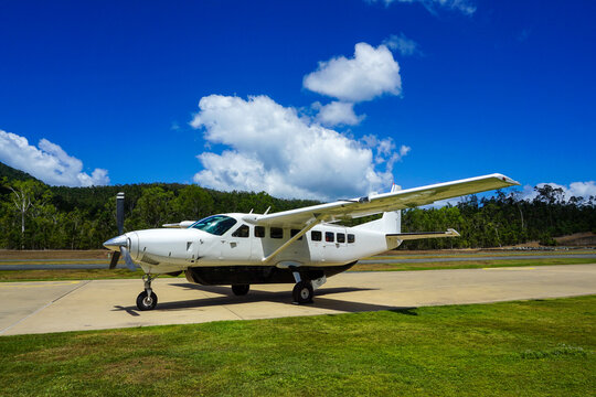 White propeller airplane parked on tropical airfield runway