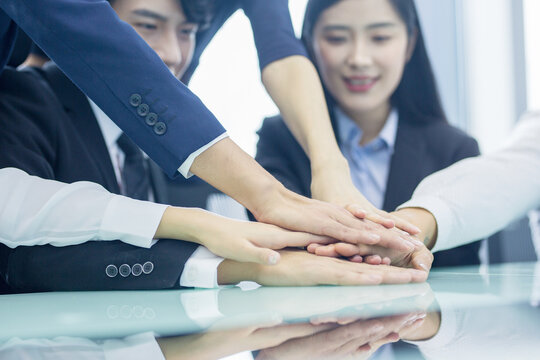 Business team stacking hands in office for teamwork and unity