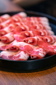 A hotpot meat platter presents thinly sliced beef, pork, and chicken arranged neatly on a serving plate. Close-up compositions emphasize beef marbling, pork color, and the natural fiber patterns of ch