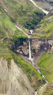 4K Vertical shot of Sissu waterfall falling from a cliff during the monsoon season as seen from mountain near Sissu village in Lahaul and Spiti district, Himachal Pradesh, India. Natural background.