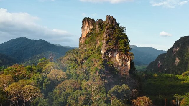 Lush green tropical rainforest covering dramatic limestone karst mountains under clear sky in Khao Sok National Park, Thailand natural beauty and unique geology. Aerial view drone flight panorama