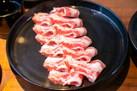 A hotpot meat platter presents thinly sliced beef, pork, and chicken arranged neatly on a serving plate. Close-up compositions emphasize beef marbling, pork color, and the natural fiber patterns of ch
