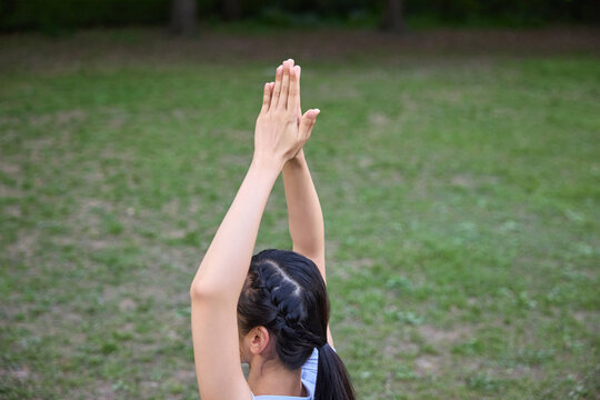 Young woman practicing yoga in park with raised prayer hands