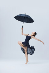 Elegant ballerina dancing with black umbrella in minimalist studio © LuuNhan