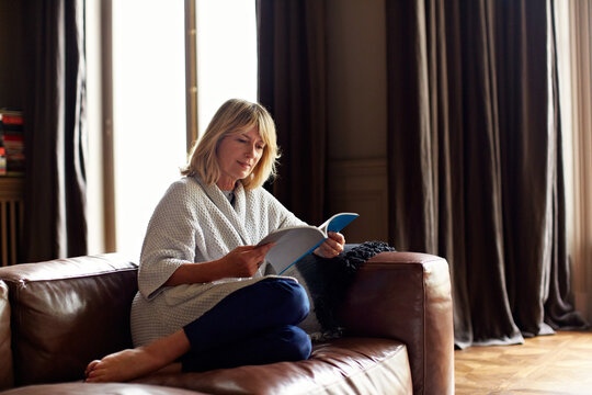 Relax, woman and reading book on sofa in home for story, learning and development information. Mature person, literature and study on couch, guidebook and self improvement hobby on weekend break