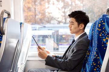 Businessman Using Tablet on Passenger Train During Autumn Commute © DaoYenThu
