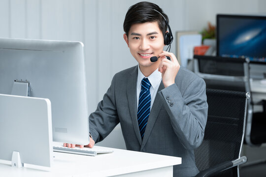 Smiling customer service representative with headset at office desk