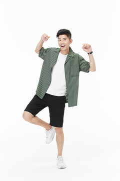 Cheerful young man dancing and celebrating in casual summer outfit on white background