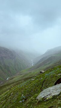 4K Vertical shot of Himalayan mountain valley covered by clouds and fog during the monsoon season as seen during the Ghepan Lake Trek near Sissu in Lahaul and Spiti district, Himachal Pradesh, India. 