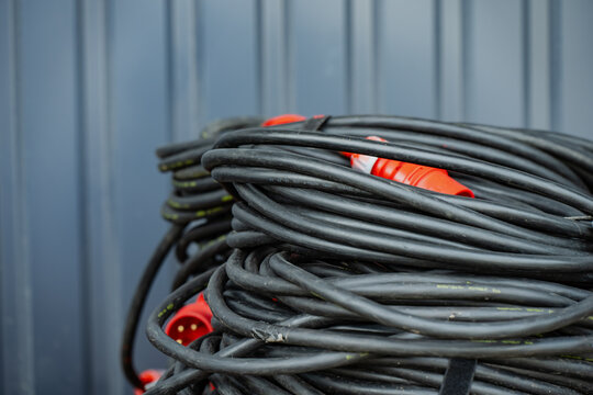 Heavy-duty industrial power cable coil with red IEC 309 three-phase electrical plug connector on a commercial construction site