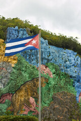 Cuban Flag Waving in Front of Mural de la Prehistoria in Viñales Valley, Cuba © Laura