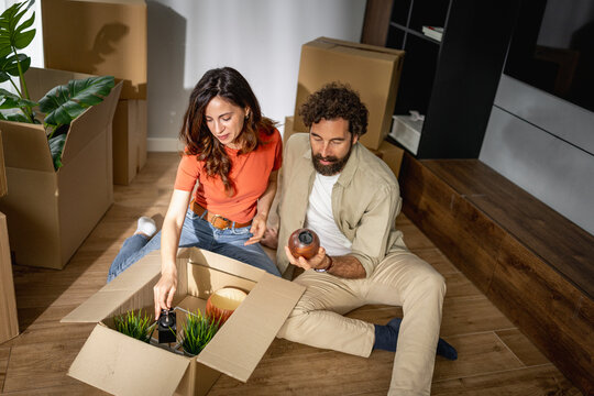 Young couple unpacking boxes and decorating new home together on moving day