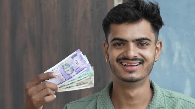 Excited young man fanning Indian Rupee notes and expressing amazement