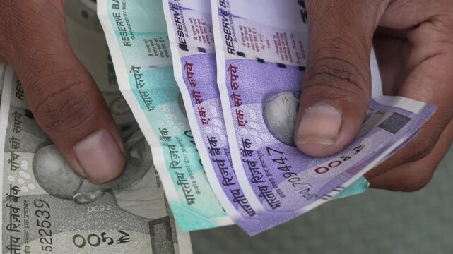 Person holding and counting Indian Rupee currency notes