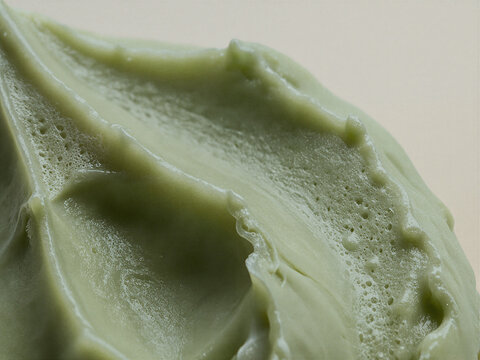 Macro Texture of Thick Green Matcha Cream or Skincare Clay Mask Swirled on Plain Background