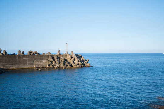 Concrete breakwater and tetrapods on blue ocean in Keelung