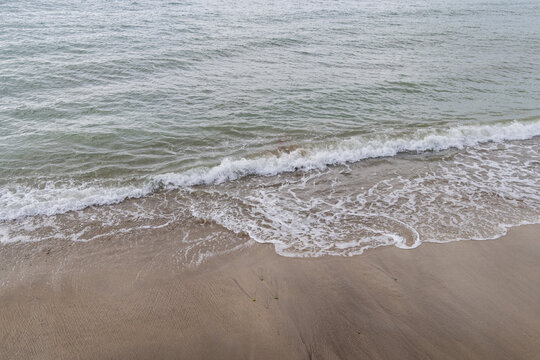 Small ocean wave coming onto sandy beach shore