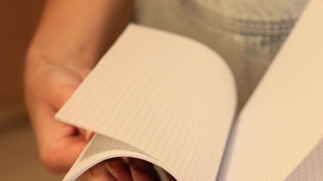 Student flipping pages of blank squared exercise book