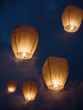 A group of five traditional Chinese Mid-Autumn lanterns recreated entirely from transparent inflatable plastic, different sizes and rounded silhouettes, each glowing with warm golden internal light