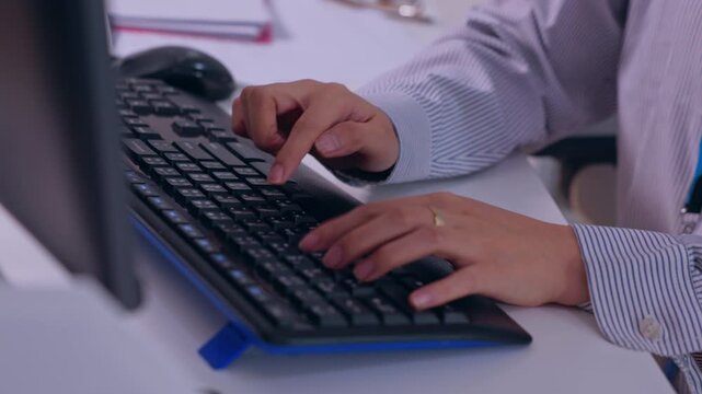 Keyboard hand typing computer office desk work business employee technology close up workplace with monitor mouse notebook striped shirt professional focus digital task