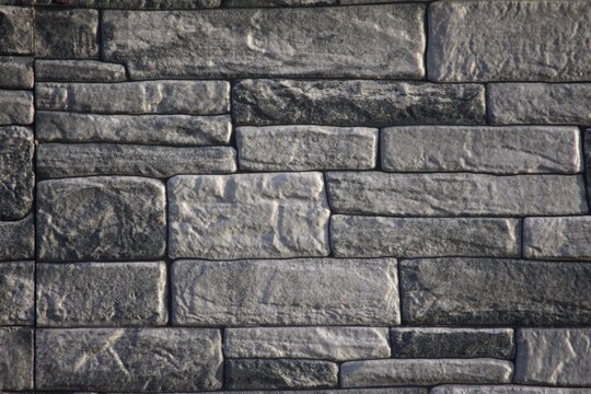 Modern horizontal stack gray stone veneer wall background texture.